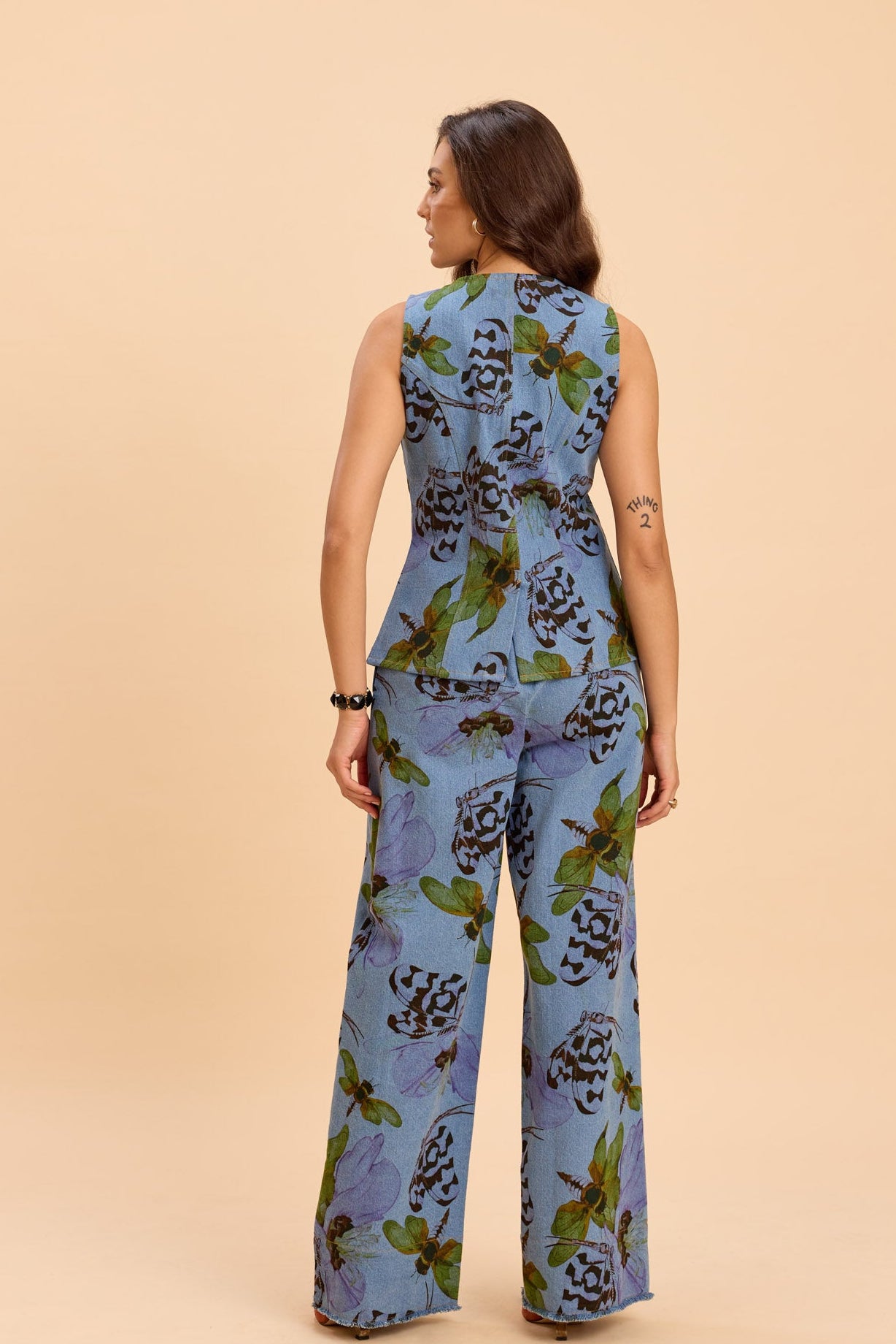Woman wearing a blue floral jumpsuit on a beige background