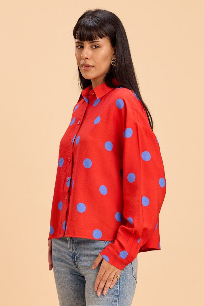 Woman wearing a red polka dot shirt and blue jeans on a beige background