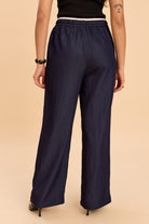 Navy wide-leg pants worn by a person on a beige background