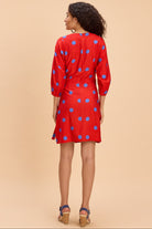 Woman wearing a red dress with blue polka dots on a beige background